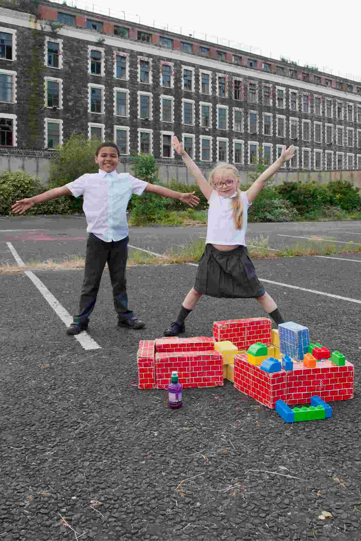 Children play on waste ground in front of disused industrial building